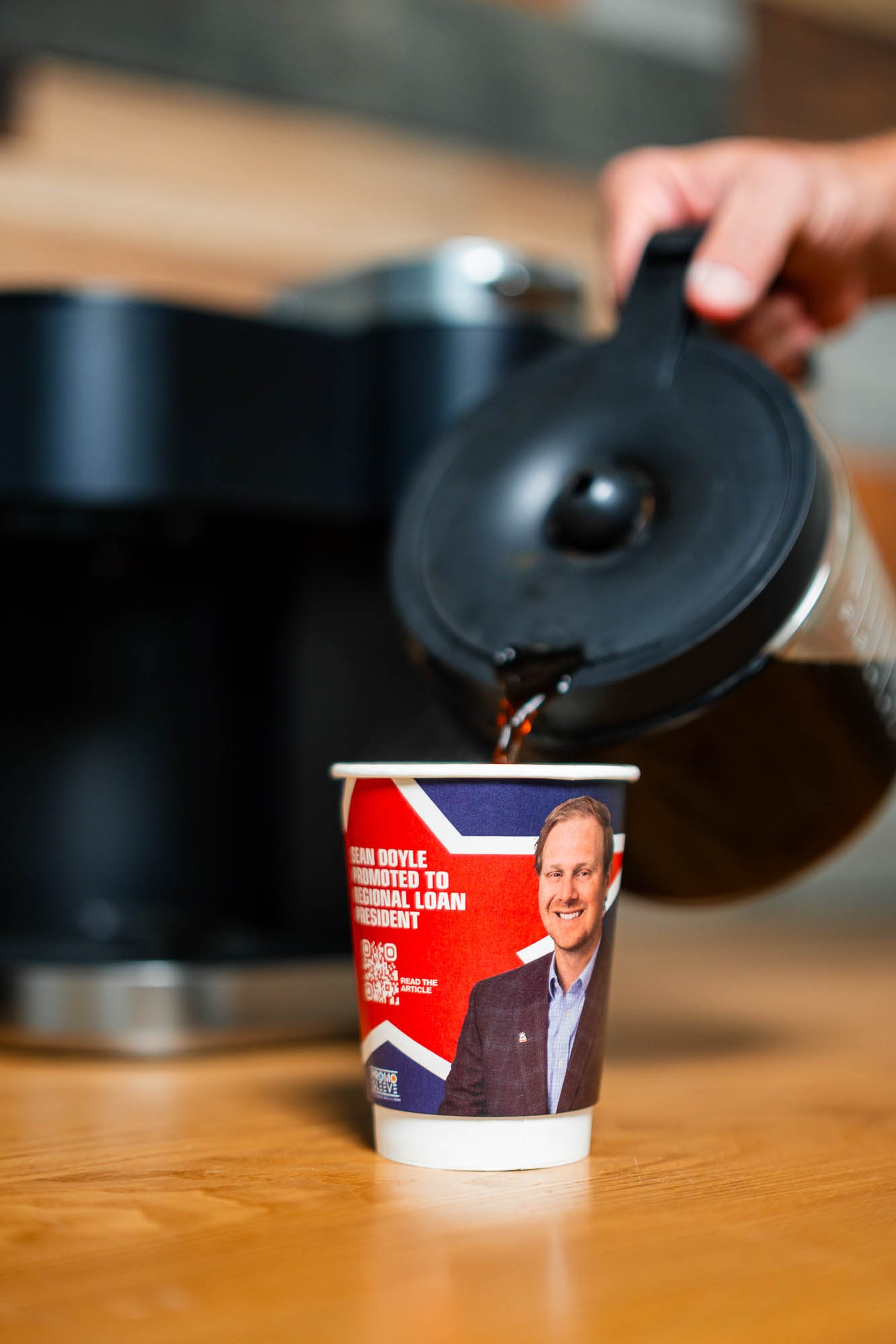 Coffee being poured into a branded cup announcing a regional employee promotion